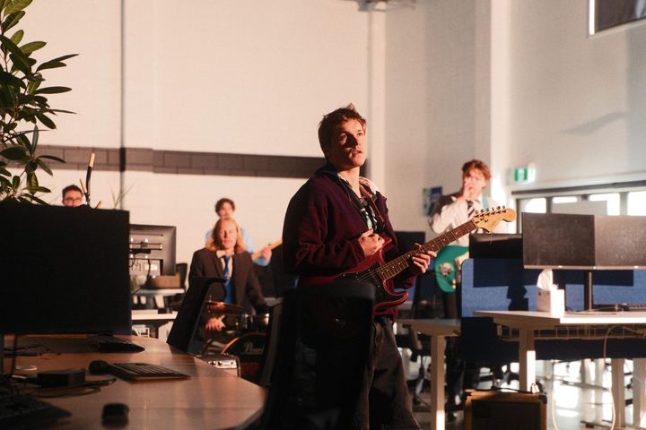 The band playing between office desks and monitors in afternoon light