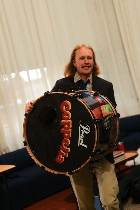 Grinning band member holding up the Coppelia bass drum in the office