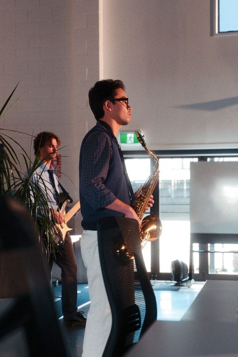 Guitarist and saxophonist performing by the office windows