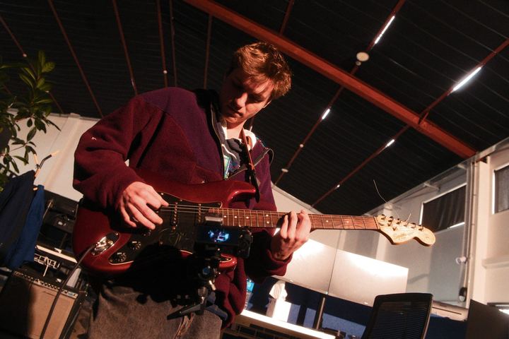 Guitarist in a red jacket playing a red electric guitar